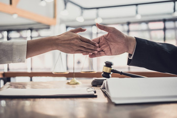 Handshake after good cooperation, Businesswoman Shaking hands with Professional male lawyer after discussing good deal of contract in courtroom, Concepts of law, Judge gavel with scales of justice