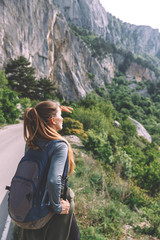 Naklejka premium Traveling woman sitting near mountain and looking far away Spring weather, calm scene. Hiking outdoors, landscape view in the sunlight. A series of photos of Wanderlust.