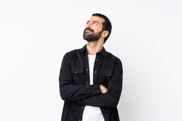 Young man with beard over isolated white background looking up while smiling