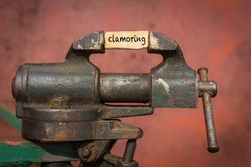 Vice grip tool squeezing a plank with the word clamoring