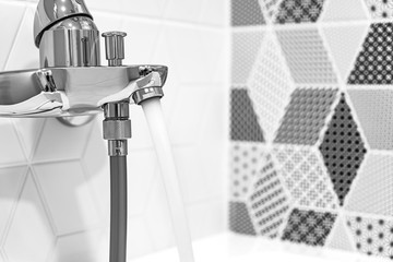A water tap with a flowing stream of water in a new bathroom with a European renovation close-up. 