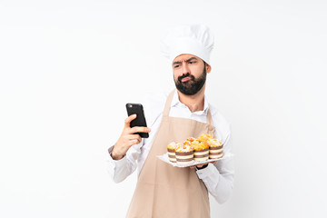 Young man holding muffin cake over isolated white background thinking and sending a message