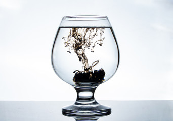 Mixing black paints with water in a transparent glass