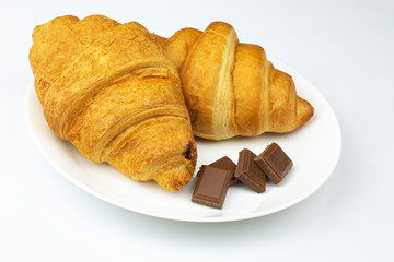 chocolate croissants and pieces of chocolate on a plate and a white background