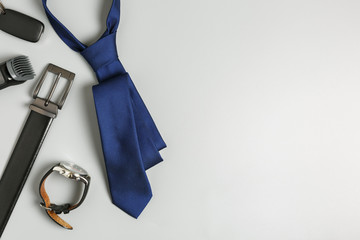  blue tie, black leather belt, watch, razor, car keys on a gray background. happy father's day holiday concept. flat lay of men's accessories.