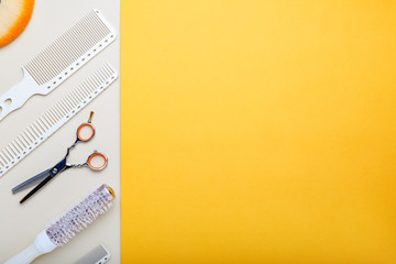 Hairdresser tools, hair salon equipment for professional hairdressing in beauty salon, haircut service. Top view with copy space on orange background. White hairbrush, comb, scissors, brush