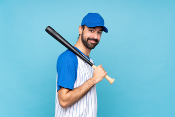 Young man playing baseball over isolated blue background with arms crossed and looking forward