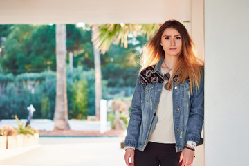 Obraz premium beautiful charismatic girl in a light sweatshirt v denim jacket with long blonde hair on a summer day