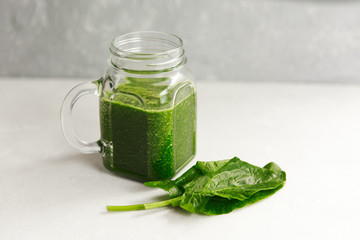 Green smoothie from broccoli, spinach, kiwi and banana on a light background. Eco concept. Healthy green smoothie and ingredients on white - superfoods, detox, diet, health, vegetarian food concept.