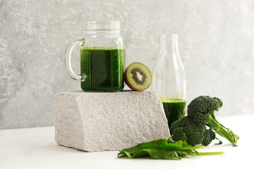 Green smoothie from broccoli, spinach, kiwi and banana on a light background. Eco concept. Healthy green smoothie and ingredients on white - superfoods, detox, diet, health, vegetarian food concept.