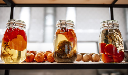 Jars of pickles are on the shelf in the kitchen. Pickled vegetables