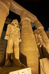 Ancient egyptian temple columns and statues at night