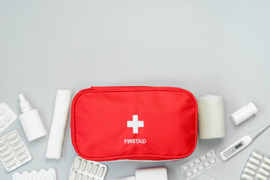 First Aid Kit Red Bag With Medical Equipment And Medications For Emergency Treatment. Top View Flat Lay On Gray Background. Copy Space. 