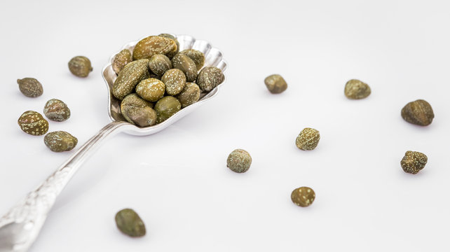 Capers in a spoon isolated on a white background. Bunch canned pickled or salted capers.