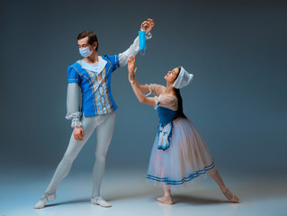 Modern Cinderella not trying the slipper on, but protective face mask. Young and graceful ballet dancers during show on studio background. Art, motion, action, flexibility, inspiration concept.