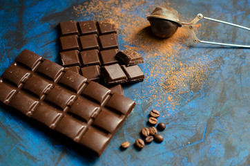 bar of dark chocolate on a blue background with sprinkled cocoa