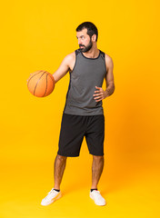 Full-length shot of a man playing basketball over isolated yellow background