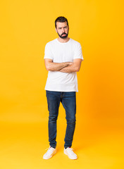 Full-length shot of man with beard over isolated yellow background with sad and depressed expression