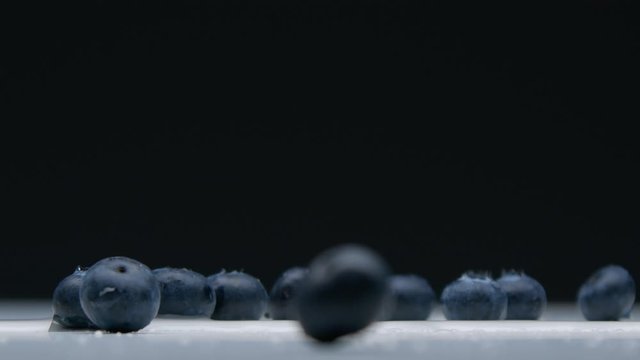 side view of blueberry falling to the desk with water splashes Super slow motion from 120 fps
