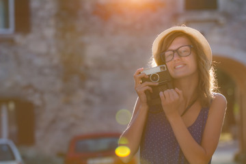 Cute young tourist woman with vintage retro camera on the street.
