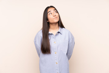 Obraz premium Young Indian woman isolated on beige background and looking up