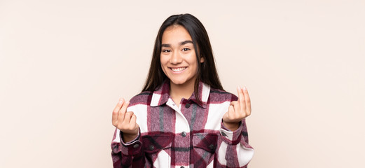 Young Indian woman isolated on beige background making money gesture