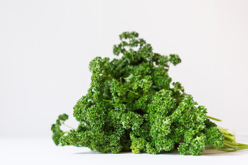 Obraz premium A bunch of fresh curly parsley on the white background. Seasoning greens on the table. Healthy vegetarian food. An ingredient for salad.