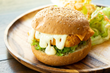 Fried fish fillet burger with vegetable salad on wood plate background