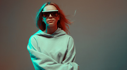 Portrait of a stylish young girl, cool posing in a hoodie, sunglasses and with developing hair, on...