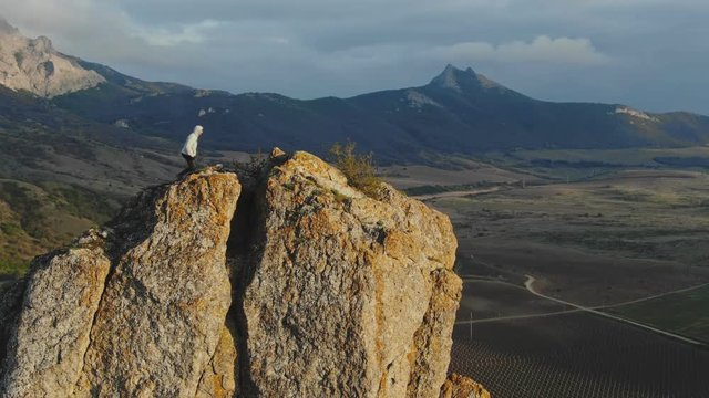 Aerial footage swoops around the cliff on which the man climbed and looks at the mountain panorama and the valley below