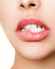 Obraz premium Close-up of the white teeth of a woman biting her lips