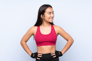 Fototapeta na wymiar Young Indian sport woman isolated on blue background posing with arms at hip and looking side