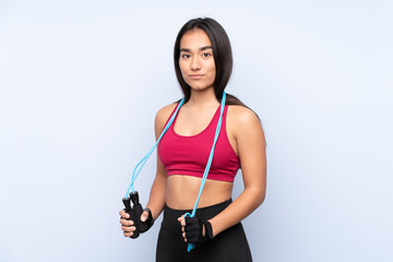 Young Indian sport woman isolated on blue background with jumping rope