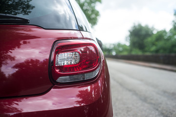 Closeup of rear light of red car parked in the street