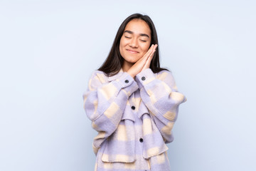 Young Indian woman isolated on blue background making sleep gesture in dorable expression