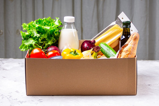 Donation box with various food. Open cardboard box with oil, vegetables, milk, canned food, cereals and pasta. Food delivery concept with space for text.