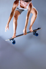 Fototapeta na wymiar Skateboarder doing trick with longboard in front of grey wall.