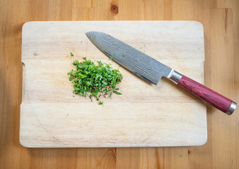fresh herbs finely cut or chopped with a damask knife on a wooden board