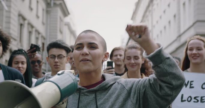 Group of young people protest against their civil rights. Woman with megaphone leading the protest on the street.
