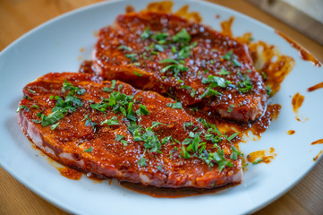 fresh neck steak of pork marinated with paprika and oil with fresh herbs on top ready to grill