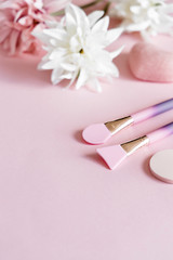 Cosmetic products: silicon spatulas and sponges on pink and white textile flowers background. Beauty spa concept. 