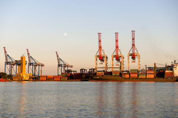 The cranes in the port of Odessa at sunset with the moon in the background.