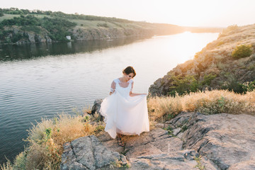 Bride in a luxurious white wedding dress in nature at sunset