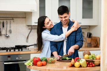 Young couple preparing salad together at home