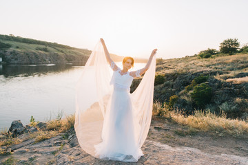 Fototapeta na wymiar Bride in a luxurious white wedding dress in nature at sunset