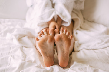 girl sitting on the bed and shows her feet