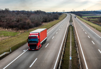 Red truck on a beautiful country highway road - business, commercial, cargo transportation concept