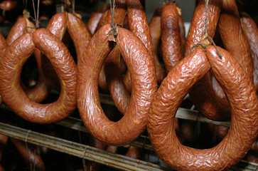 Smoked sausages hanging on a metal frame in the smokehouse.