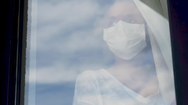 Woman in quarantine for Covid-19 looking out the window with eyes of hope