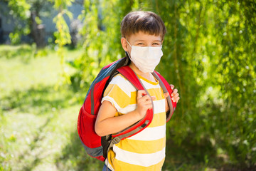 Schoolboy wearing medical face mask with backpack outdoors. Back to school. end of a quarantine